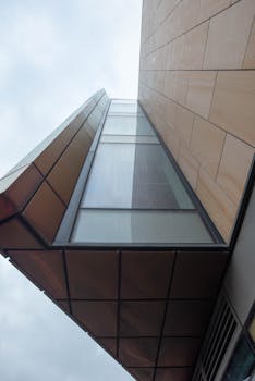 A striking view of contemporary architecture capturing geometric shapes and glass facade from below.