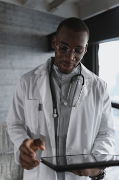 Medical professional focusing intently as he uses a tablet device indoors.