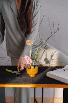 Woman arranging flowers on a table, embracing mindful home routines.