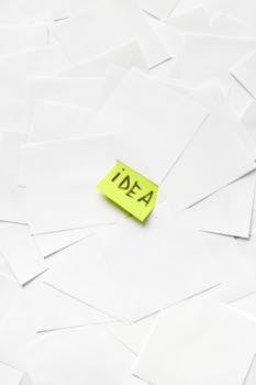 A stack of white papers with a bright yellow sticky note labeled 'idea' showcasing creativity.