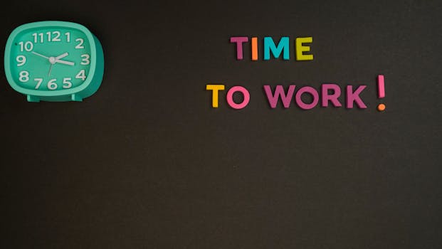 Minimalist image with a colorful clock and letters spelling 'Time to Work' on a black background.